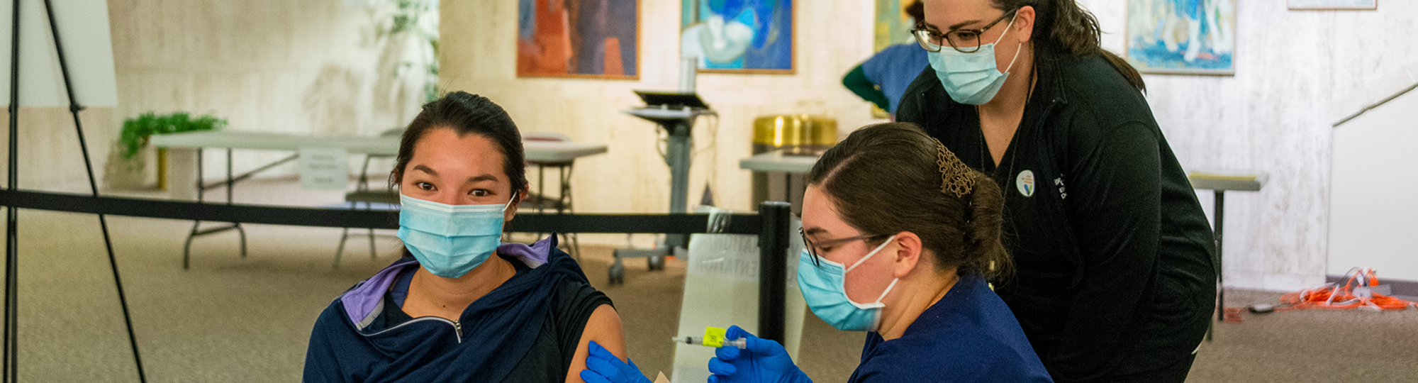 A nursing student administers an injection as a faculty member supervises